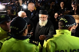 En präst pratar med polismän vid biopremiären av 'And then we danced' i Tbilisi, Georgiens huvudstad.
