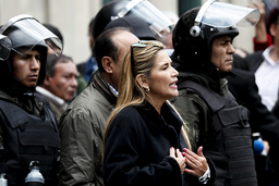 Bolivias interimspresident Jeanine Áñez talar med poliser framför presidentpalatset i La Paz.