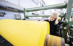 Lessebo Papers marknadschef Carina Jensen vid en rulle med rapsgult papper på Lessebo bruk i oktober 2020.