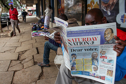 En man i Nairobi läser en tidning vars framsida visar de två ledande presidentkandidaterna Raila Odinga och William Ruto. Bilden är från i lördags.