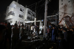 Palestinier vid en förstörd byggnad efter en israelisk attack mot ett flyktingläger i Rafah i Gaza. Arkivbild.