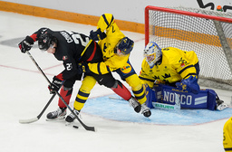 Sveriges målvakt Melker Thelin ser på medan backen Viggo Gustafsson kämpar mot Kanadas Easton Cowan i kampen om pucken.