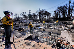 Brandmän inspekterar resterna av nedbrunna byggnader i stadsdelen Pacific Palisades i Los Angeles på fredagen.