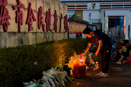 En man tänder ett ljus utanför idrottsanläggningen i Zhuhai där tiotals människor dödades i november.