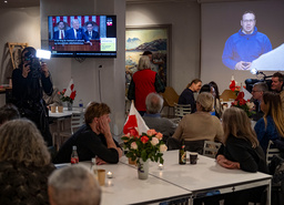 USA:s president Donald Trump och Siumuts partiledare Erik Jensen på tv respektive storbild under valvakan på Grönländska huset i centrala Köpenhamn på tisdagskvällen.