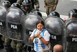 En kvinna i argentinsk landslagströja står framför kravallpolis i Buenos Aires.